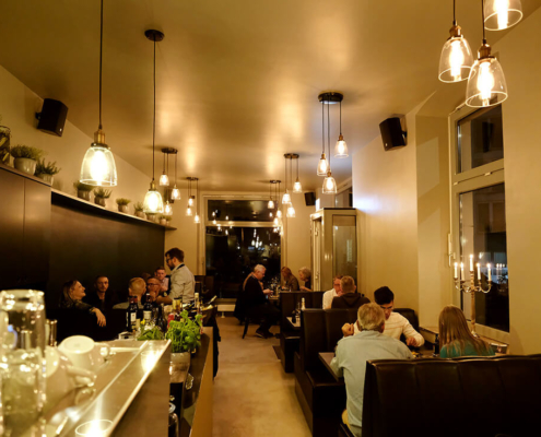 Stimmungsbild Restaurant Byliny mit Gästen, Bedienung und goldenem lichtdurchflutetem Raum.