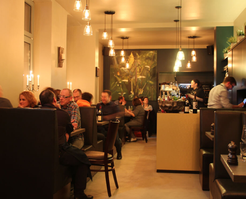 Stimmungsbild Restaurant Byliny mit Gästen, Bedienung und goldenem lichtdurchflutetem Raum